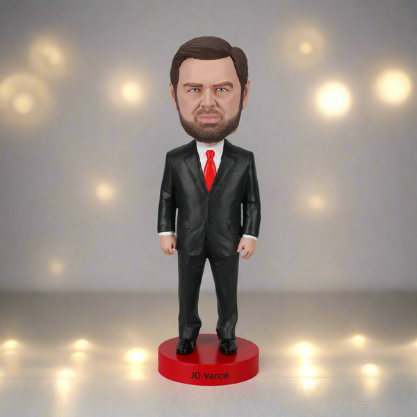 Bobblehead figure of a man in a black suit with a red tie on a white background